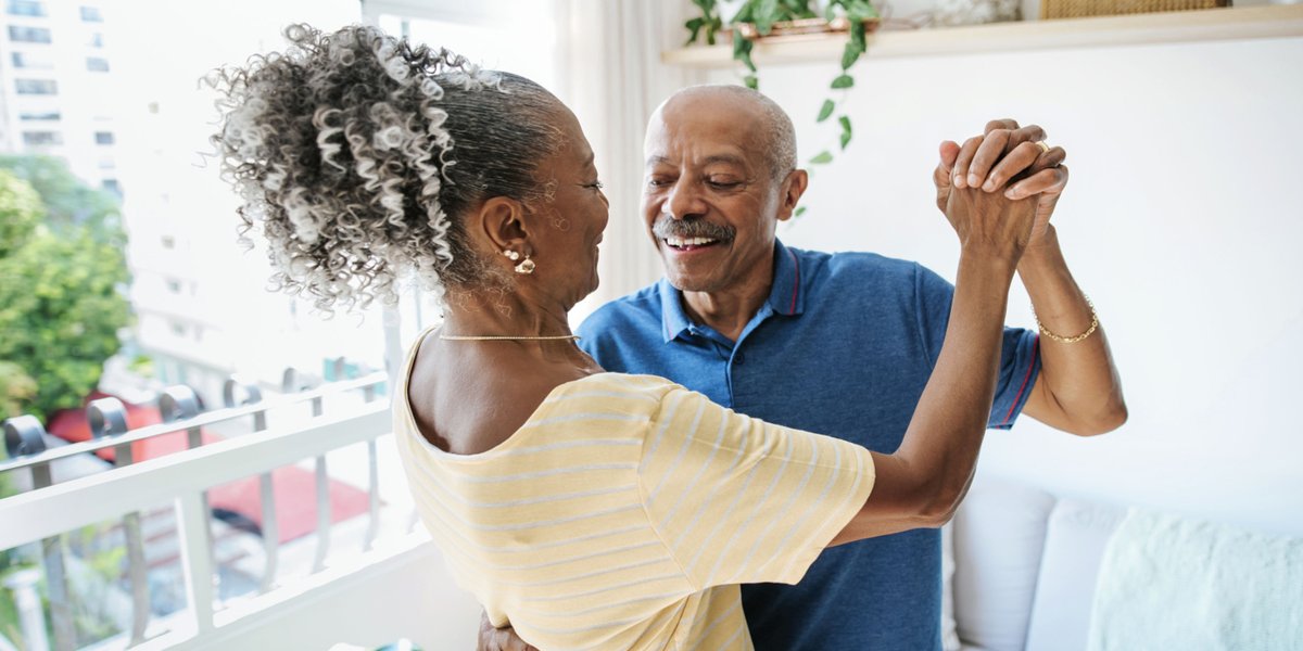 A woman in a yellow shirt and a man in a blue polo dancing in the living room
