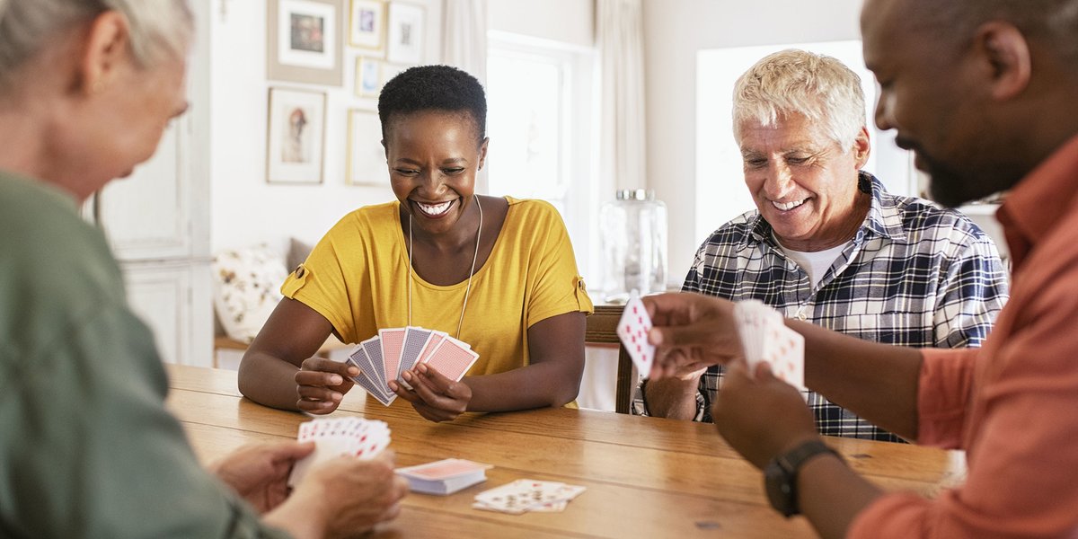 Group of 4 friends sitting at a table playing cards