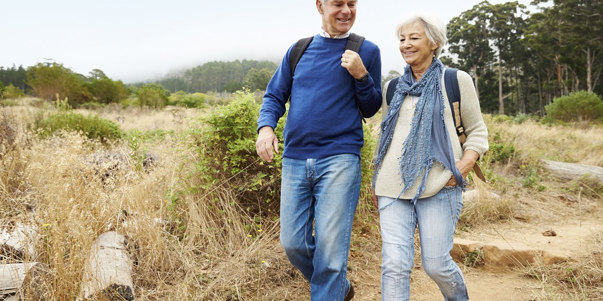 A man and a woman smiling while on a hike
