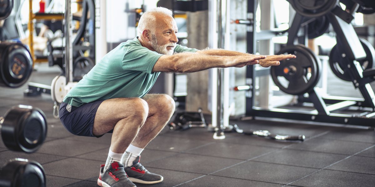 Man in a green shirt doing squats at the gym