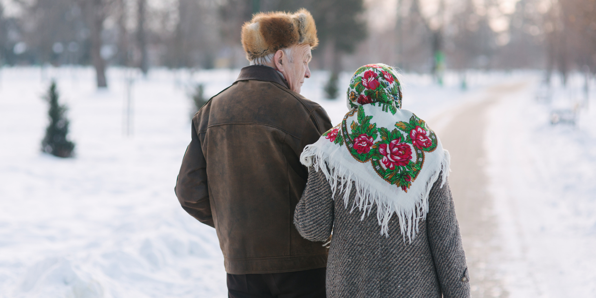 Back view of elderly couple walking in a snowy park
