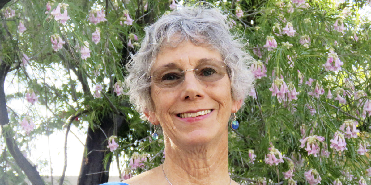 photo of Kathy McIntosh standing in front of a blooming tree