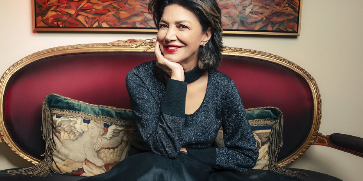 Actress Shohreh Aghdashloo in a formal dress sitting on a red loveseat