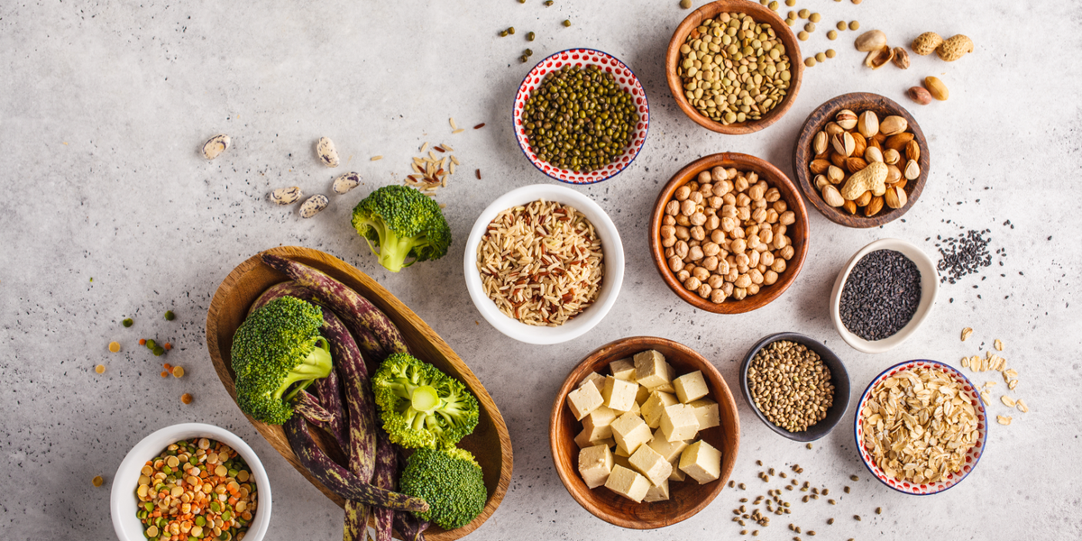 A variety of brown bowls filled with vegetables, tofu, and chickpeas on a grey table.